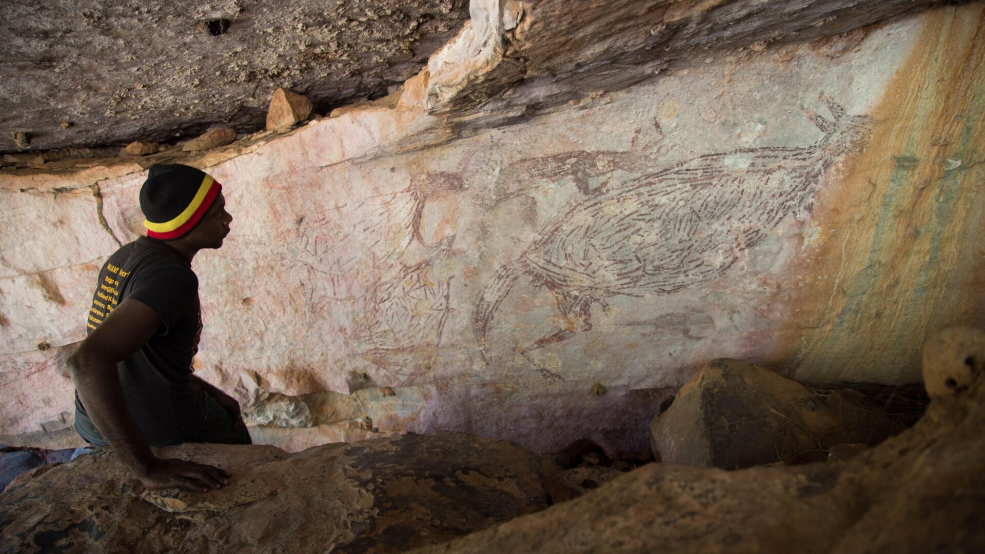 Traditional Owner, Ian Waina, observing the 17,300-year-old painting of a kangaroo.