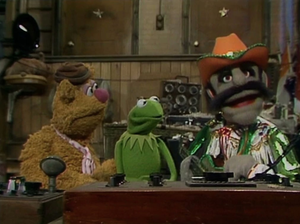 Fozzie and Kermit listening to a Muppet styled after Johnny Cash.