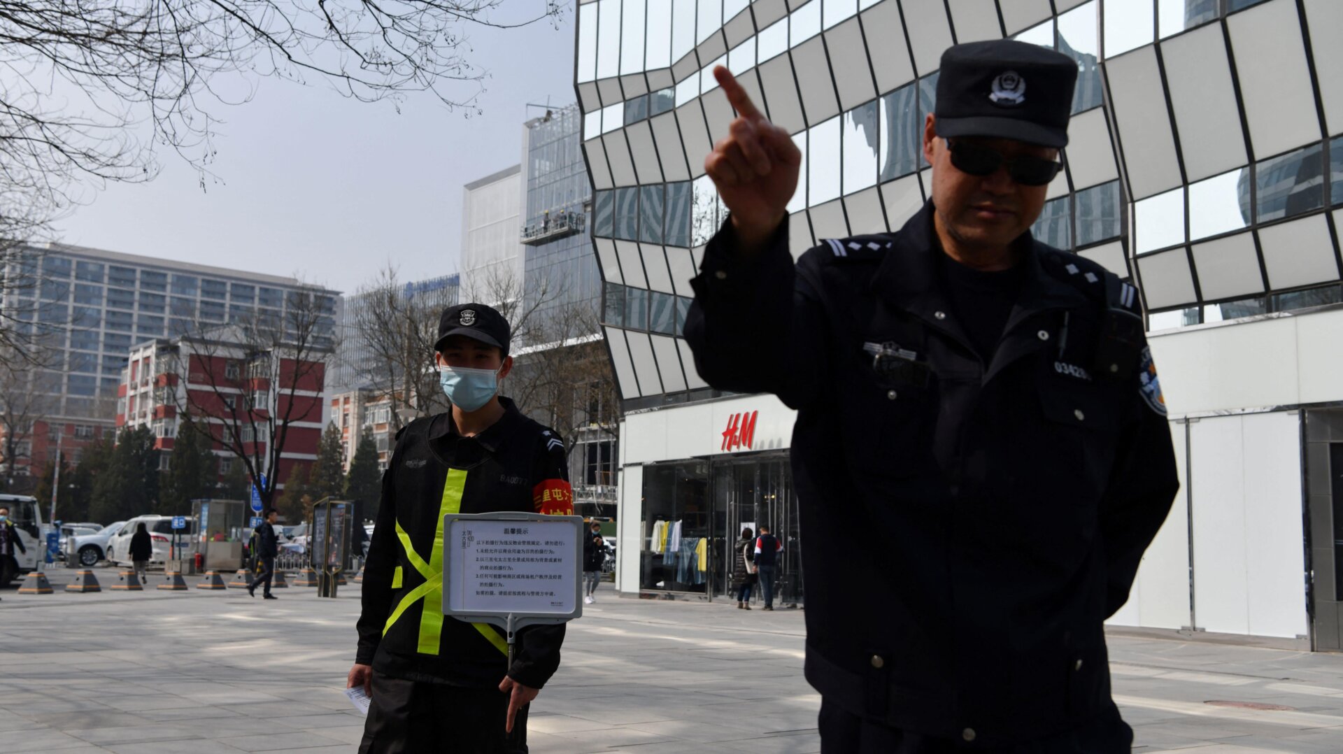 A cop tries to prevent photos from being taken outside an H&M store in Beijing on March 25, 2021.