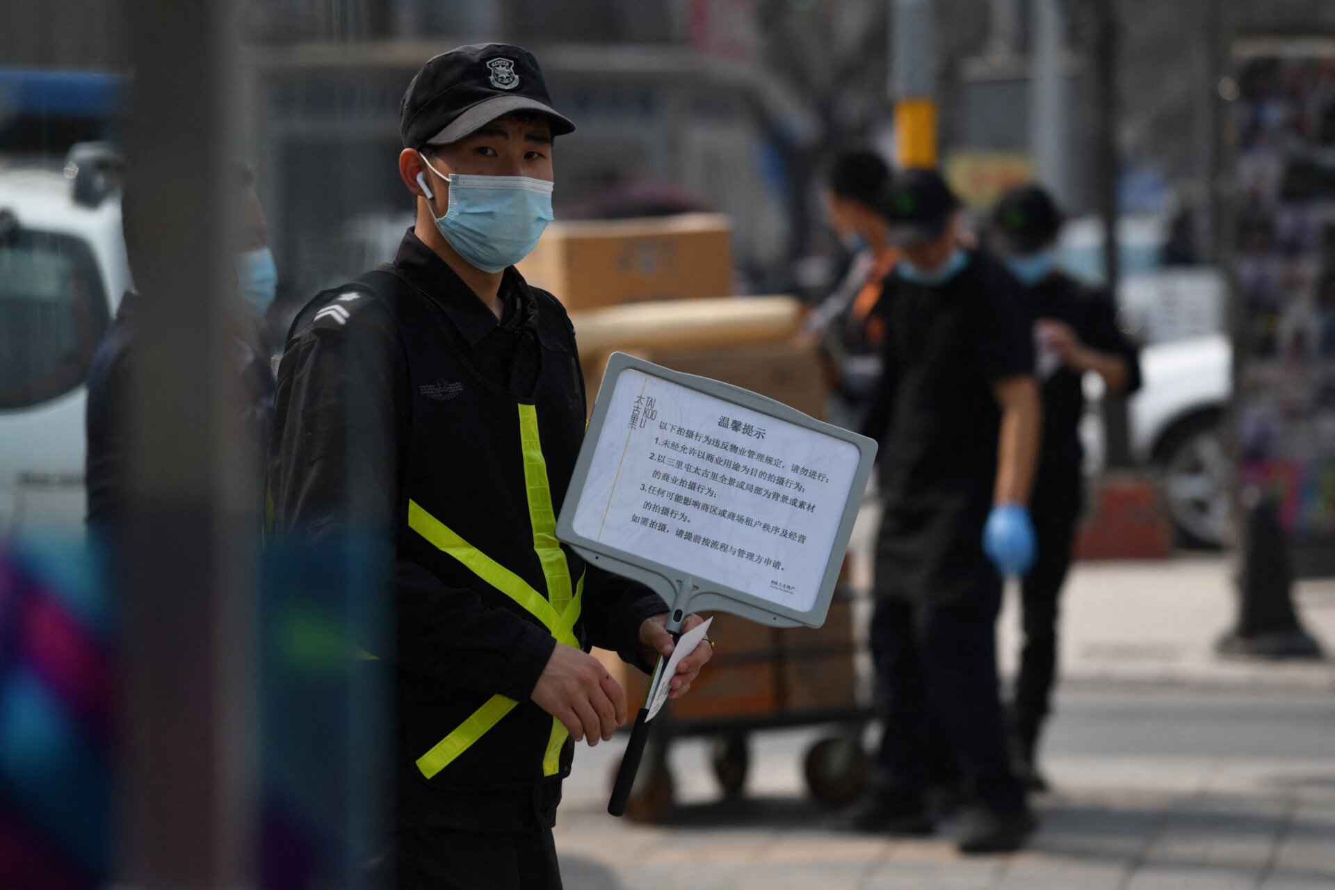 A security guard holds a sign advising that photos are forbidden without permission, outside a store of Swedish clothing giant H&M in Beijing on March 25, 2021,