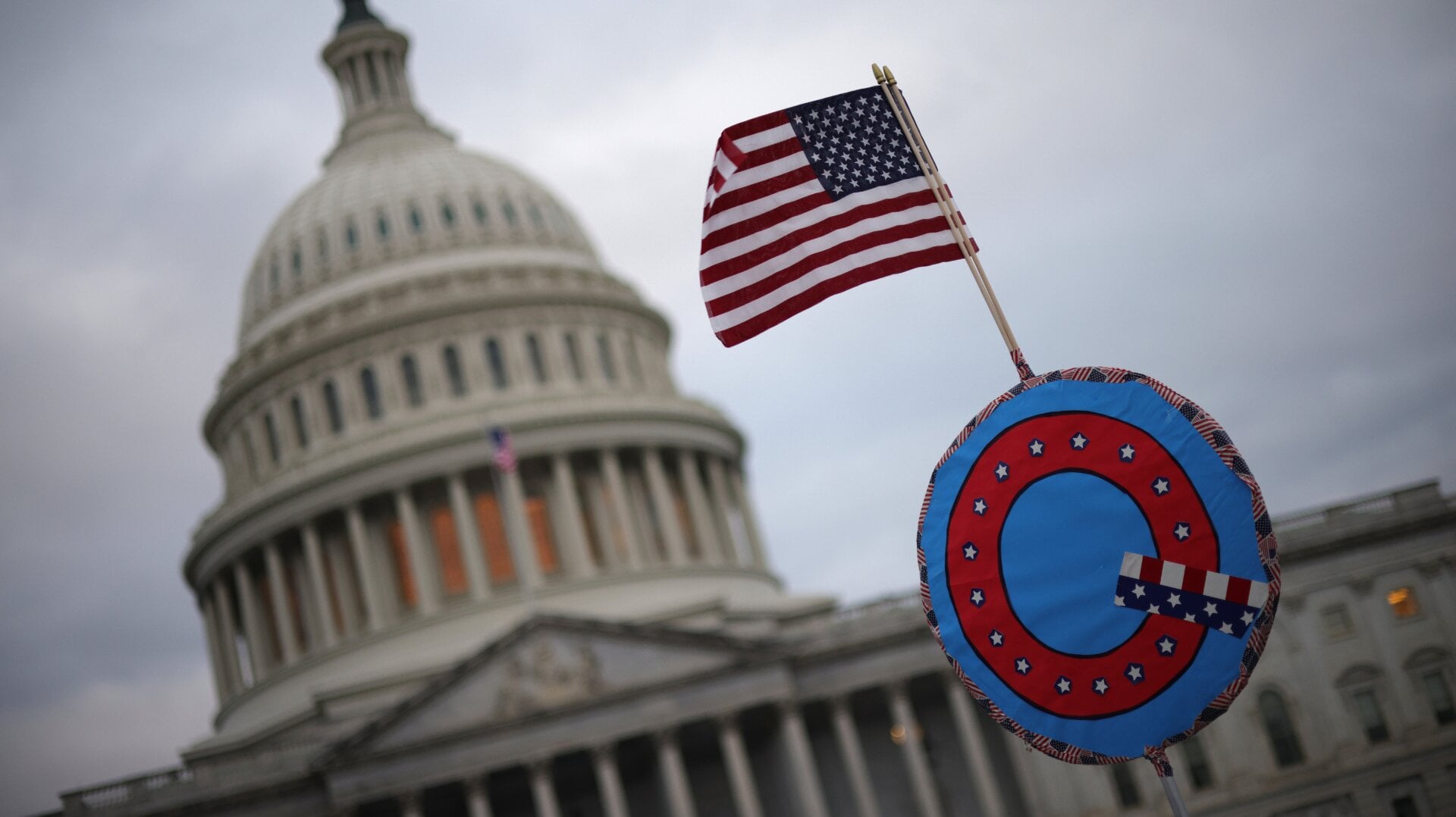 WASHINGTON, DC - JANUARY 06: Supporters of U.S. President Donald Trump fly a U.S. flag with a symbol from the group QAnon as they gather outside the U.S. Capitol January 06, 2021 in Washington, DC.