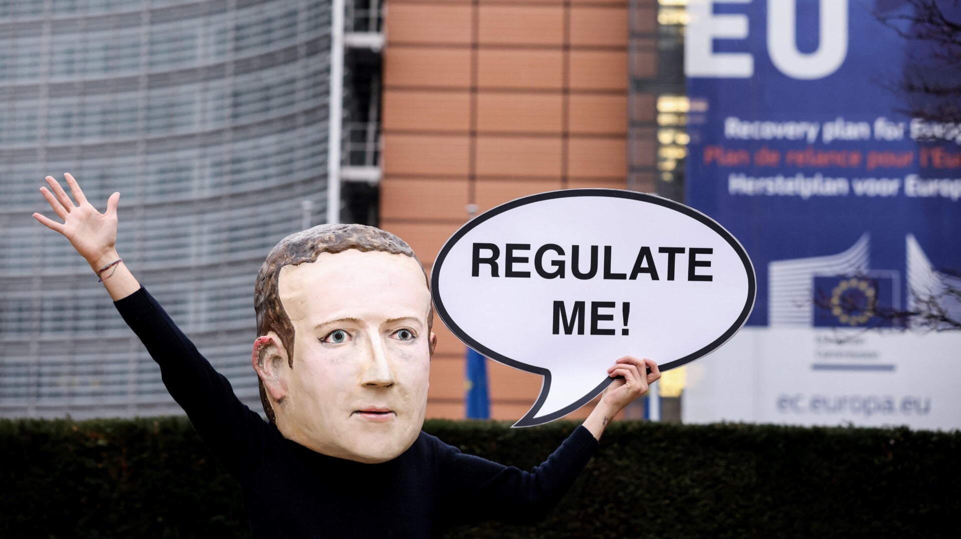An activist of environmental NGO Avaaz wearing a mask depicting Facebook CEO Mark Zuckerberg holds a banner reading “Regulate me” during an action marking the release of the Digital Services Act, outside the European Commission building in Brussels on December 15, 2020.