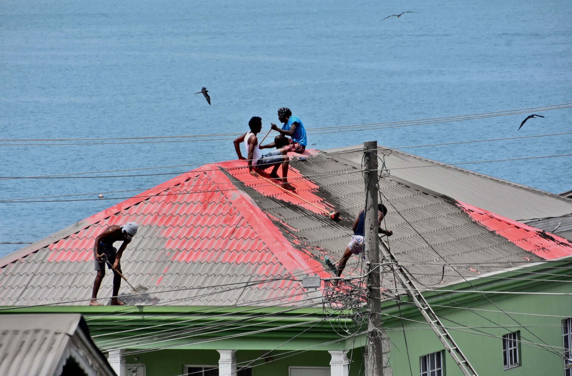 People clean volcanic ash from the red roof of a home on the western side of St. Vincent on Monday, April 12.