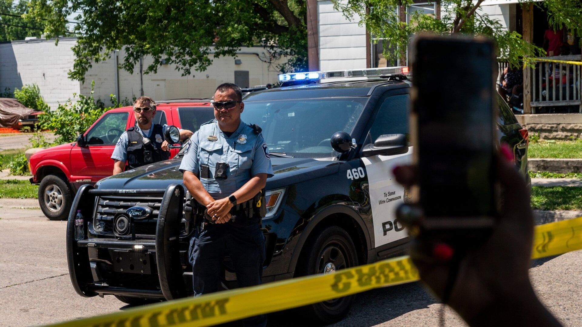 MINNEAPOLIS, MN - JUNE 16: A woman holds up her phone as Minneapolis Police officers respond at a crime scene on June 16, 2020 in Minneapolis, Minnesota. The Minneapolis Police Department has been under increased scrutiny by residents and elected officials after the death of George Floyd in police custody on May 25.