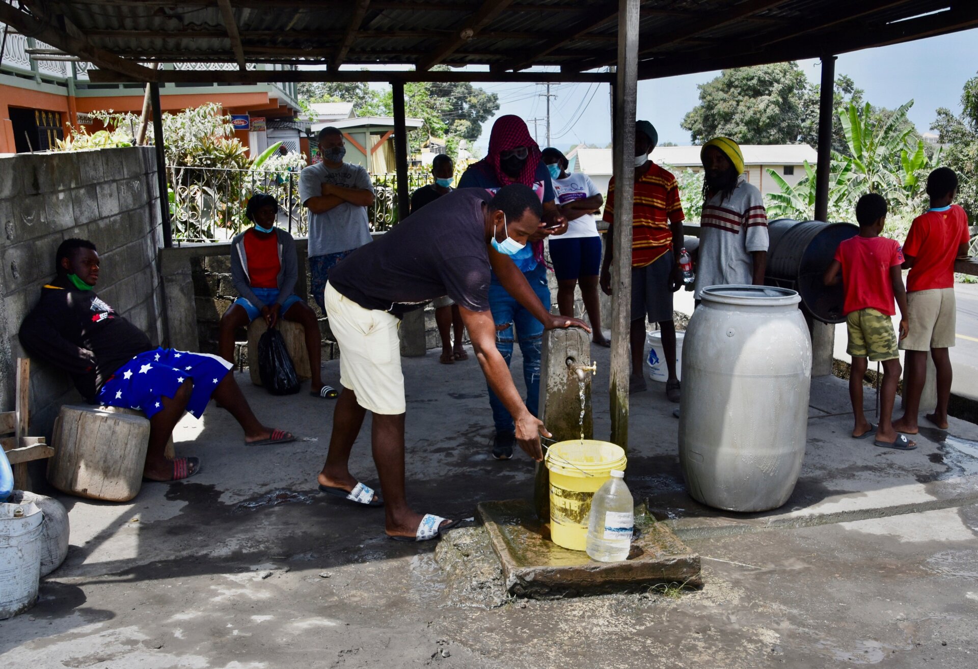 People collect water not contaminated by volcanic ash on the western side of St. Vincent on Monday, April 12.