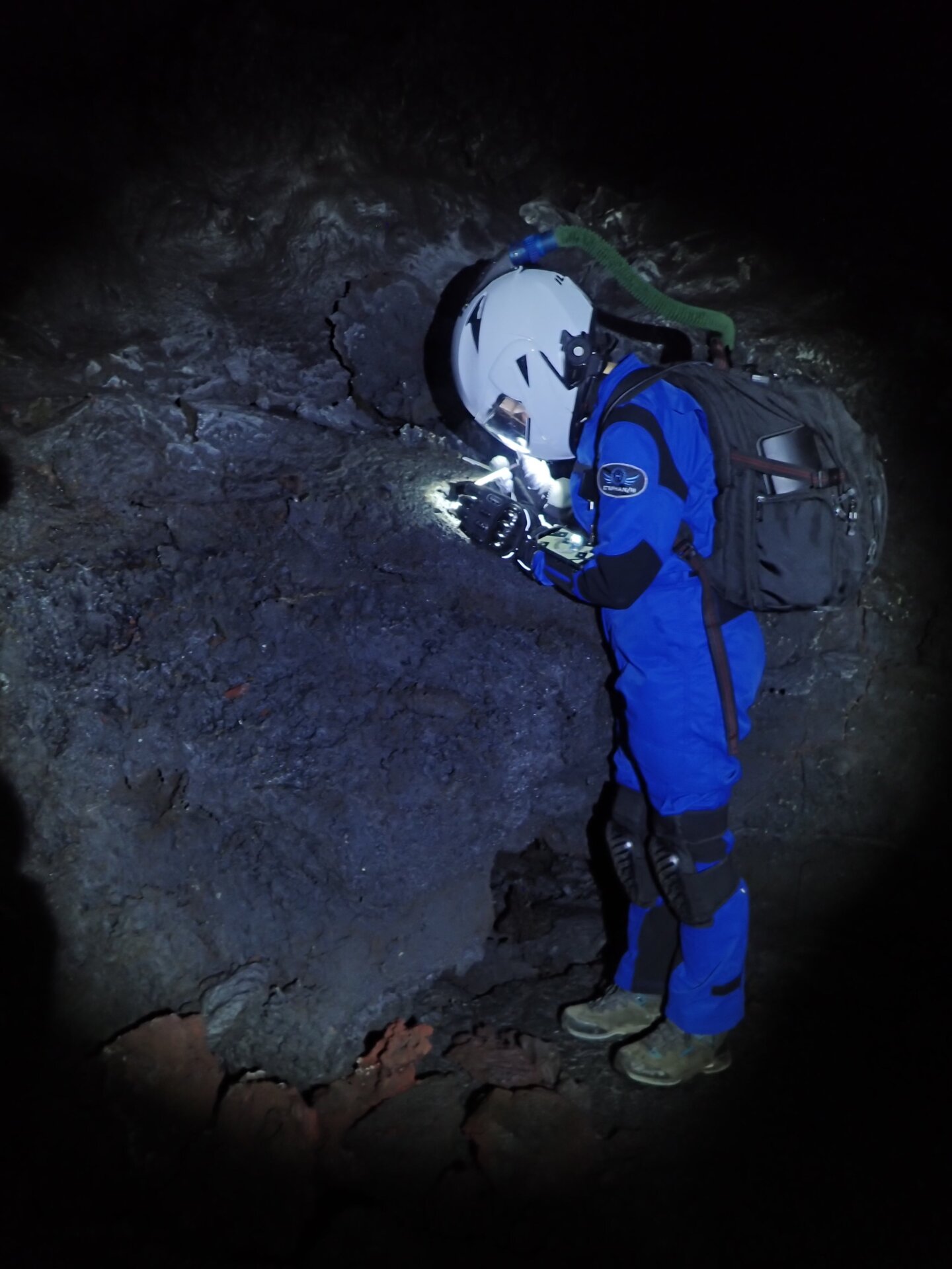 A crew member investigating rock within a Mauna Loa lava tube.