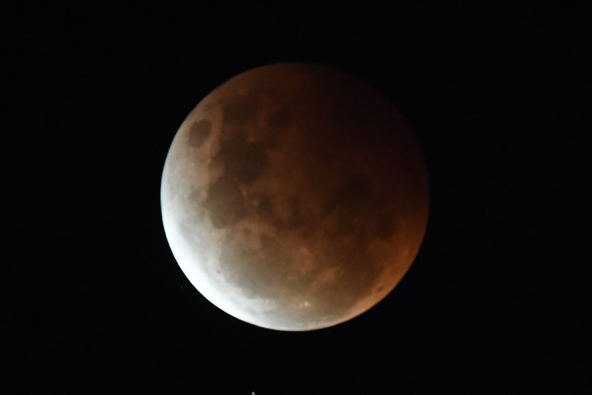 The full moon is seen during the partial eclipse in Sydney on May 26, 2021 as stargazers across the Pacific are casting their eyes skyward to witness a rare “Super Blood Moon”. 