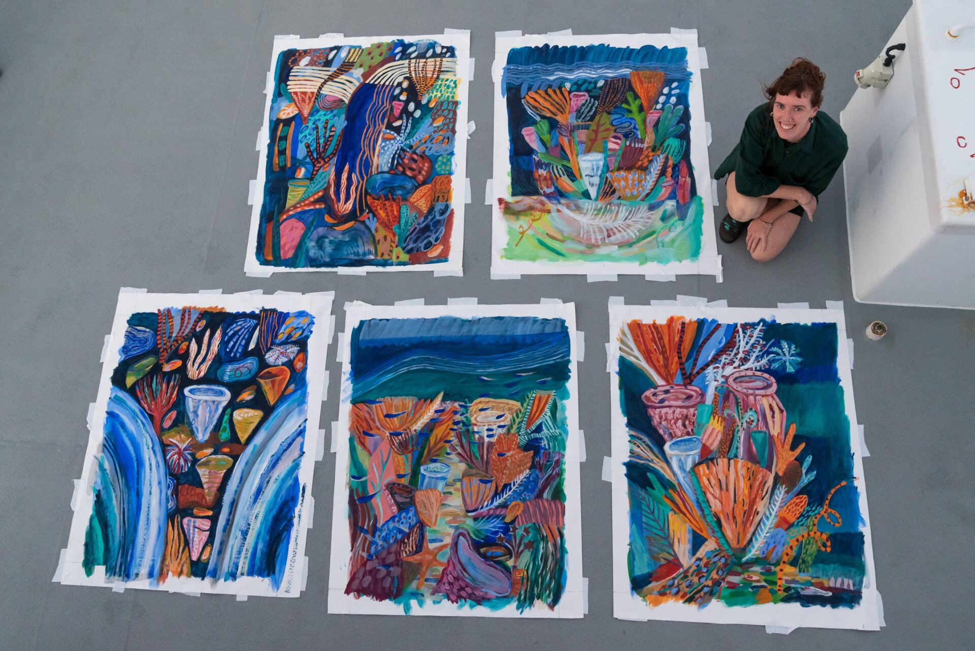 Ellie Hannon on the research vessel with the paintings she made onboard