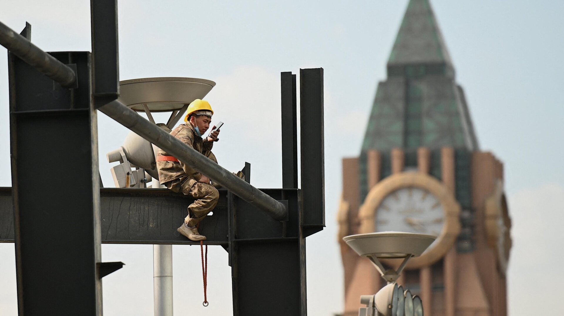 A worker uses his mobile phone at a construction site in Beijing on May 17, 2021.