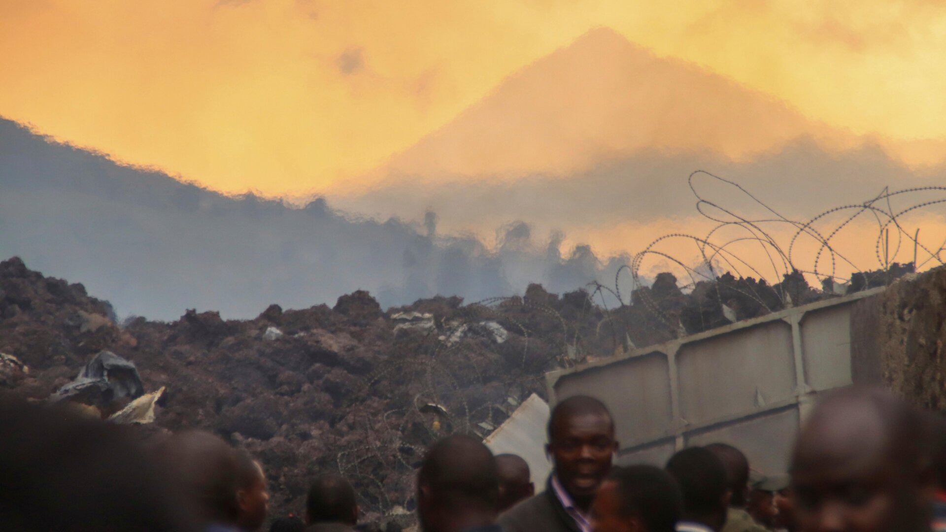 Residents check the damages caused by lava from the overnight eruption of Mount Nyiragongo, seen in the background, in Buhene, on the outskirts of Goma, Congo in the early hours of Sunday, May 23, 2021.