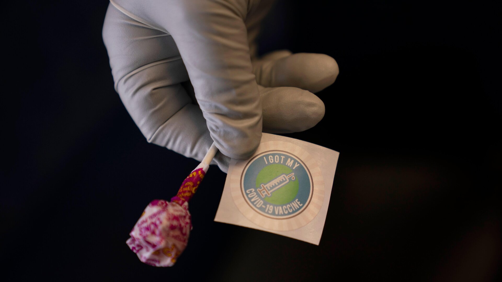 Nurse Natasha Garcia prepares a lollipop and an “I Got My COVID-19 Vaccine” sticker for a recipient in a mobile clinic set up in the parking lot of a shopping center in Orange, California.