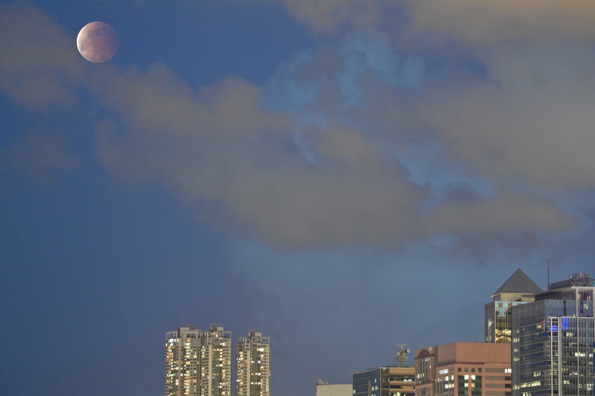 The moon is pictured above Hong Kong on May 26, 2021, during a total lunar eclipse as stargazers across the Pacific are casting their eyes skyward to witness a rare “Super Blood Moon”. 