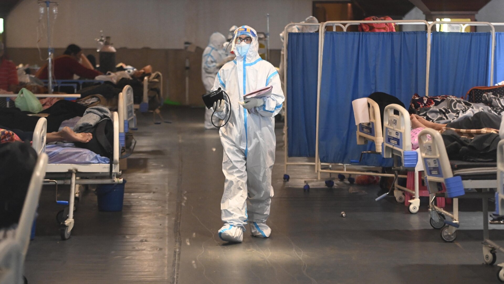 A health worker wearing a personal protective equipment kit walks inside a banquet hall temporarily converted into a covid-19 coronavirus ward in India’s capital city.