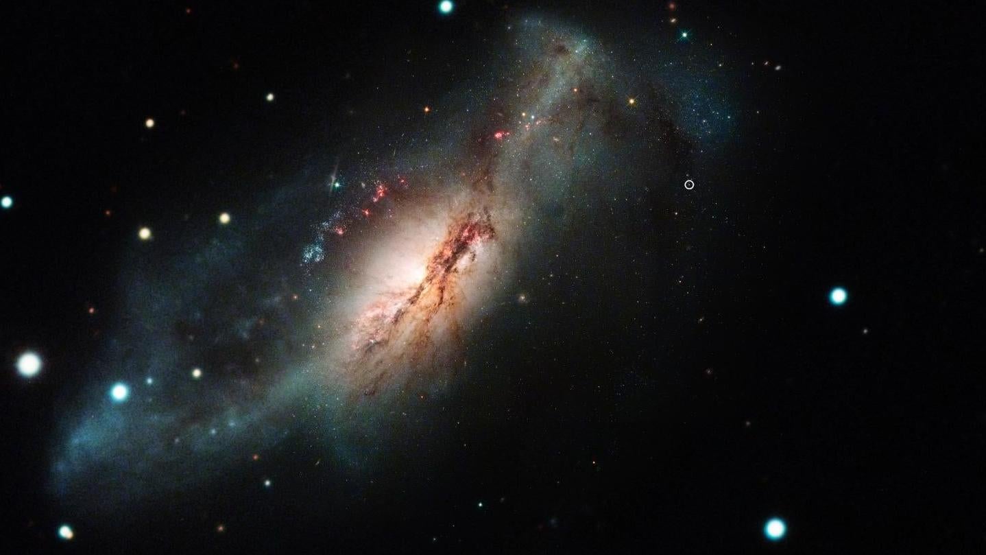 A color composite image of SN 2018zd, the bright dot at center right, and host galaxy NGC 2146 at left.