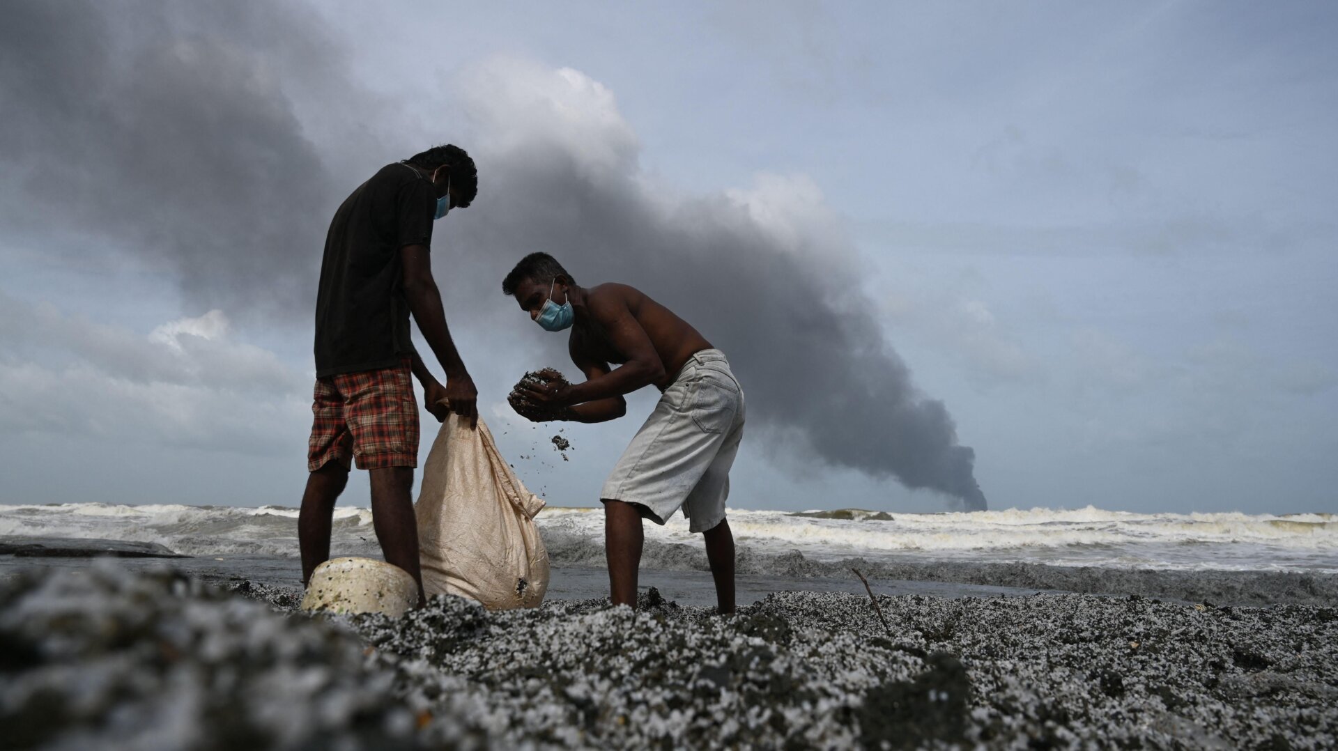 Residents collect debris among plastic pellets spilled by the ship on May 26.