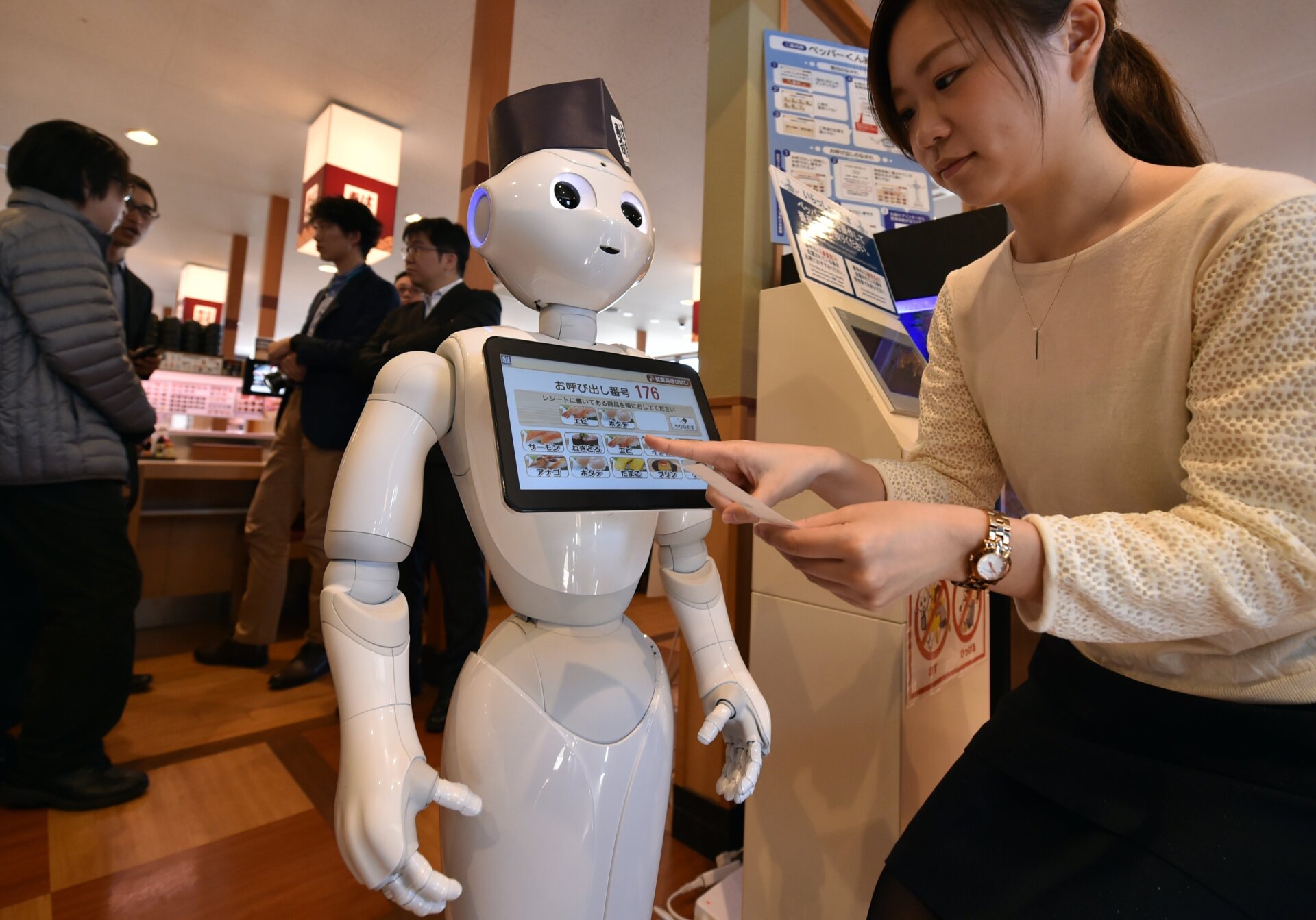 An employee of sushi restaurant Hamazushi interacts with Pepper during a press preview in Saitama, Japan on February 2, 2017.
