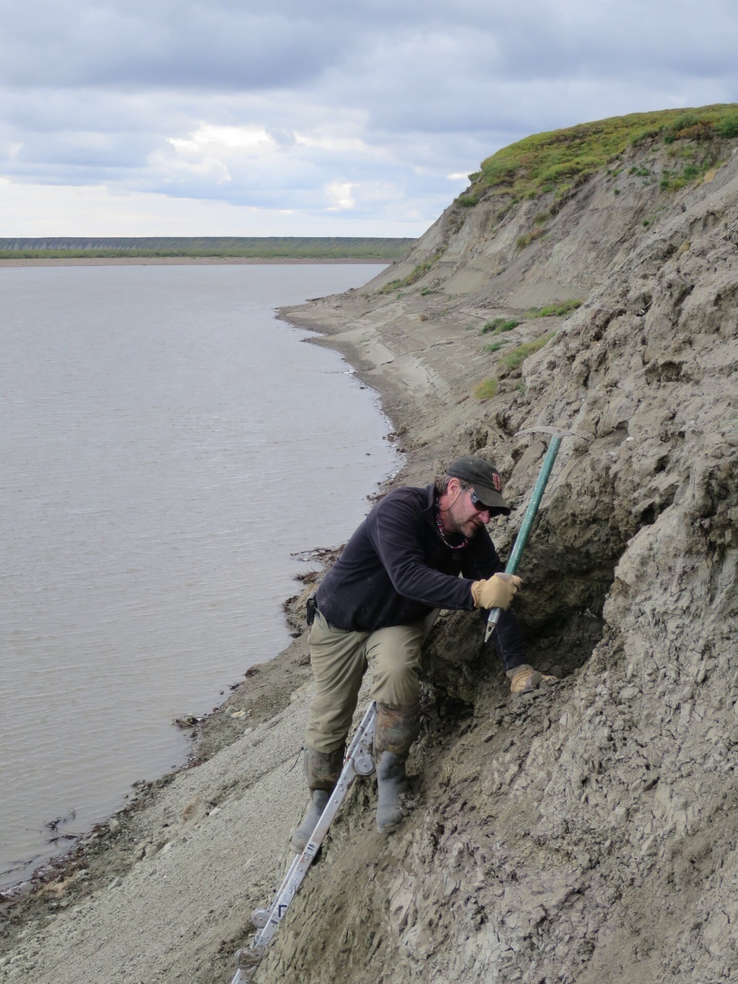 Paleontologist Greg Erickson digs through the fossil layers on the riverbank.