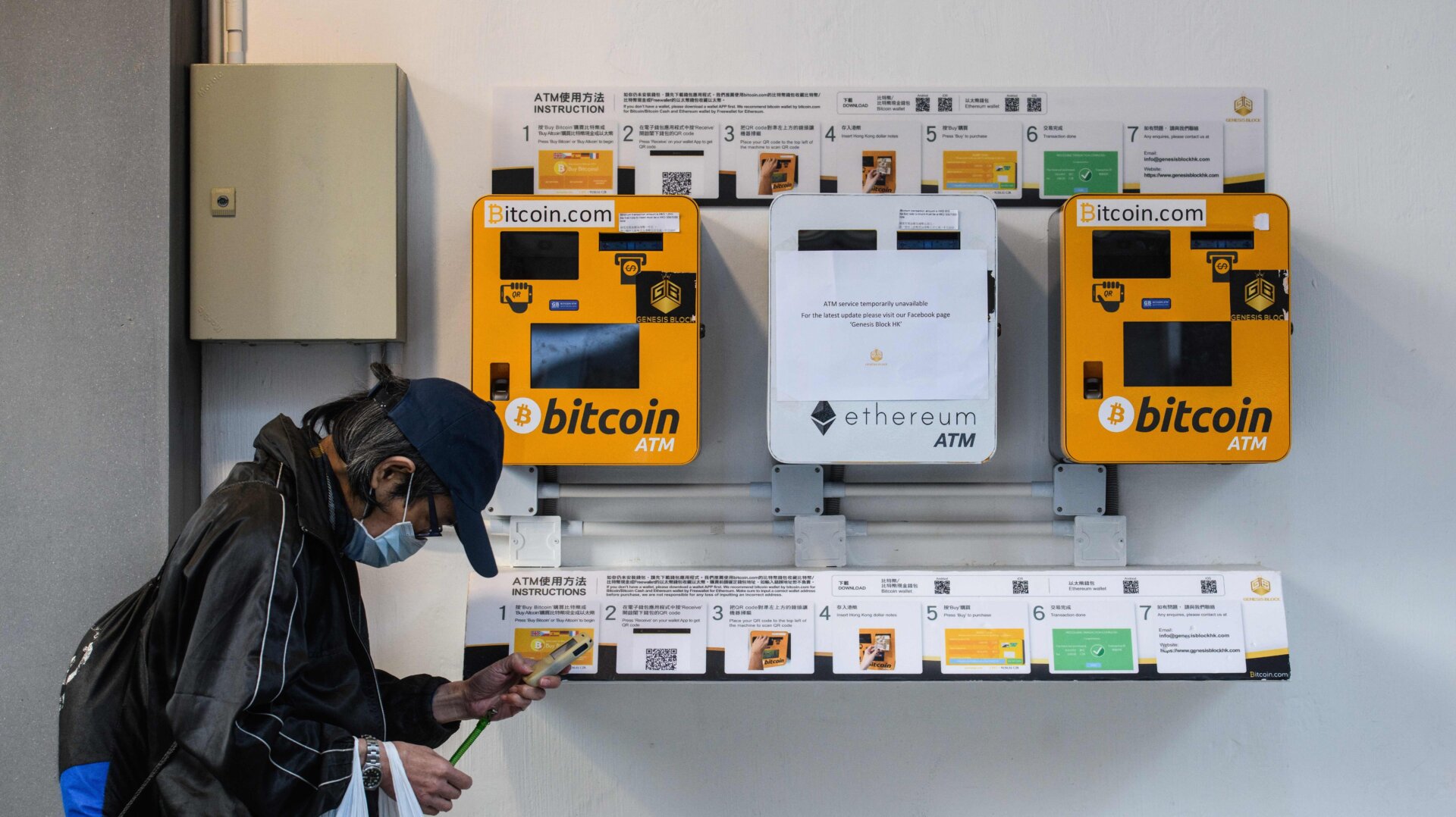 A man walks past cryptocurrency ATMs in Hong Kong in December 2017.