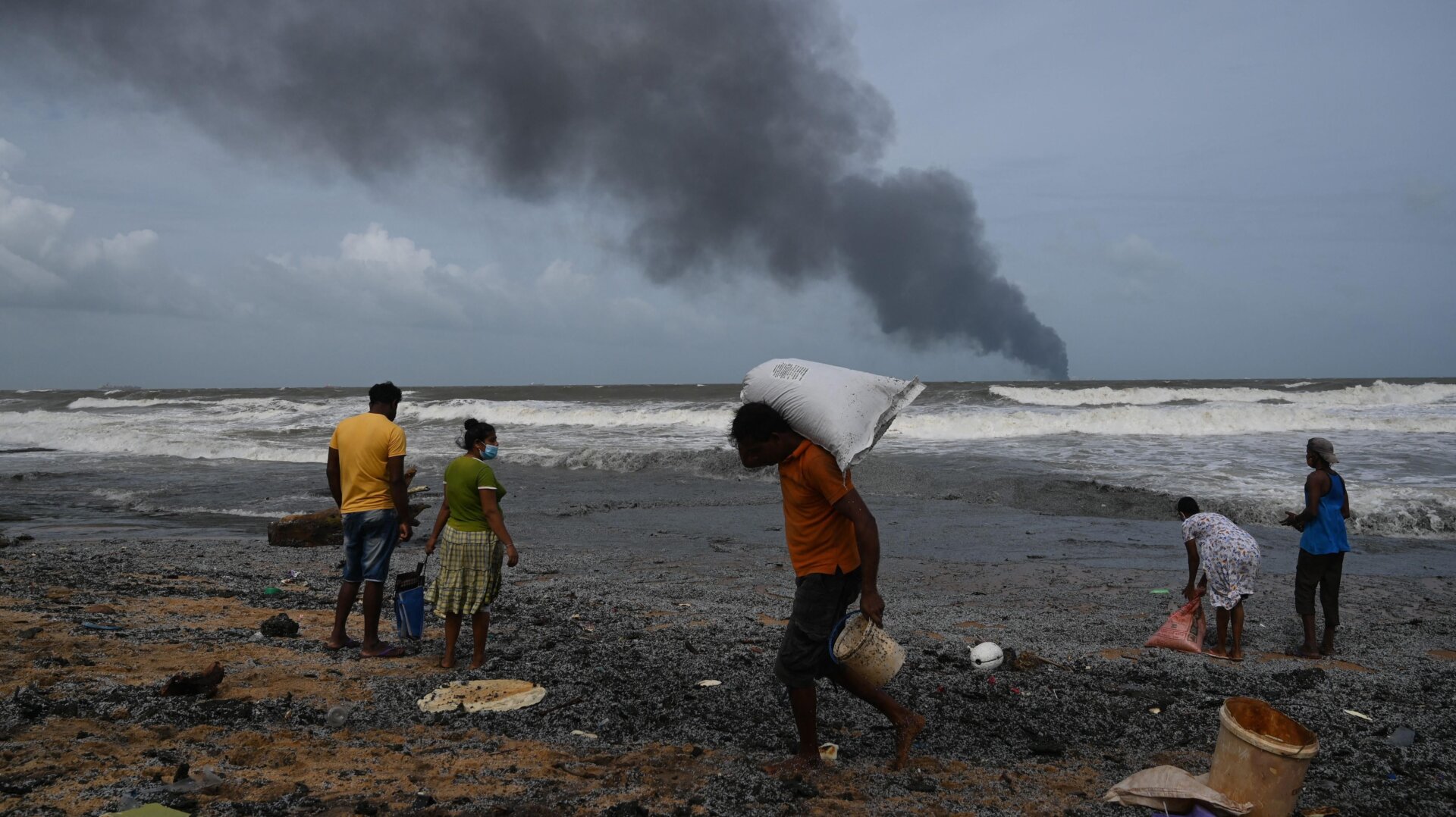 Residents collect debris from the burning ship on May 26.
