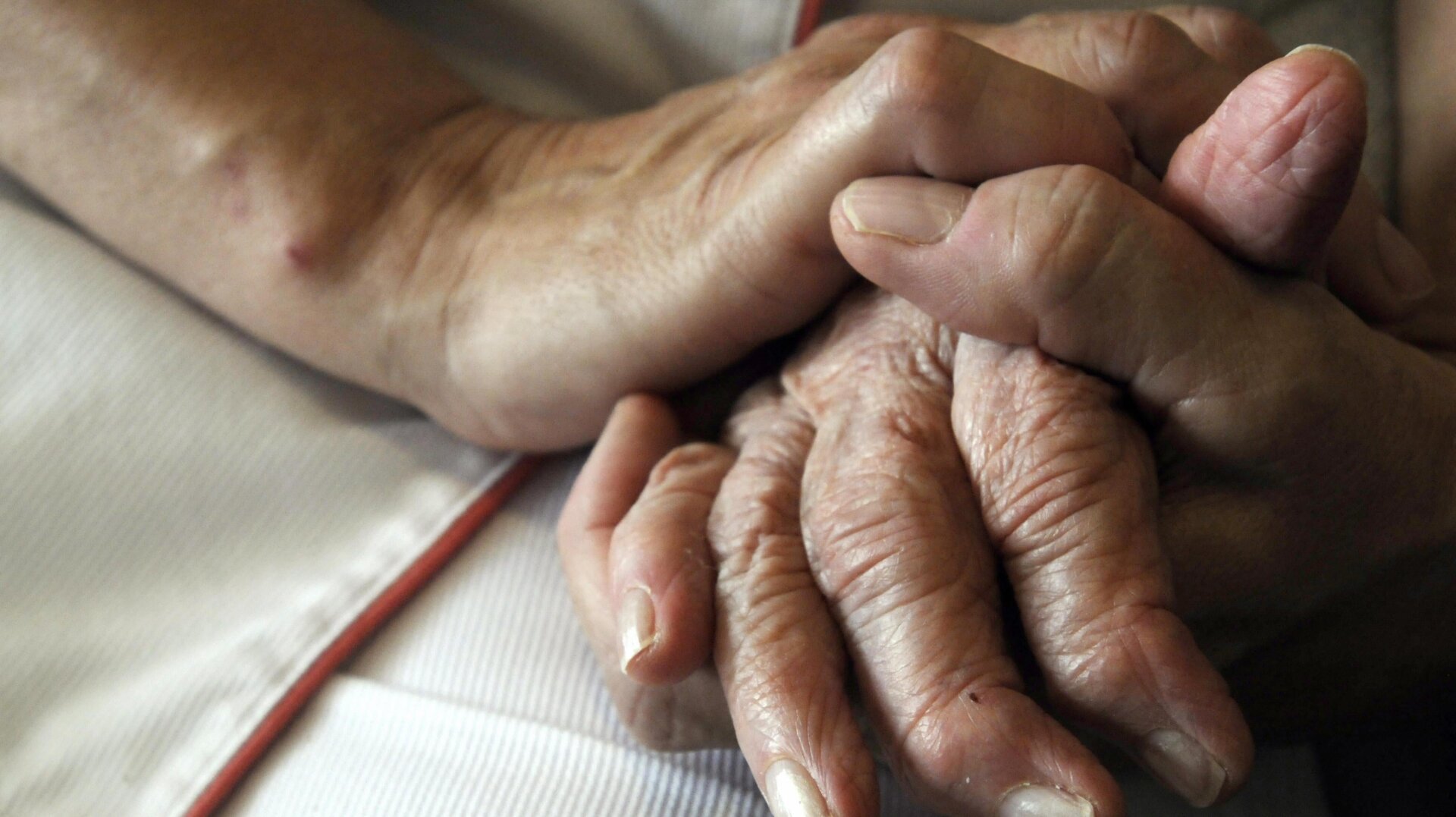 A nurse holds the hands of a person suffering from Alzheimer’s disease on September 21 2009 at the Les Fontaines retirement home in Lutterbach, France