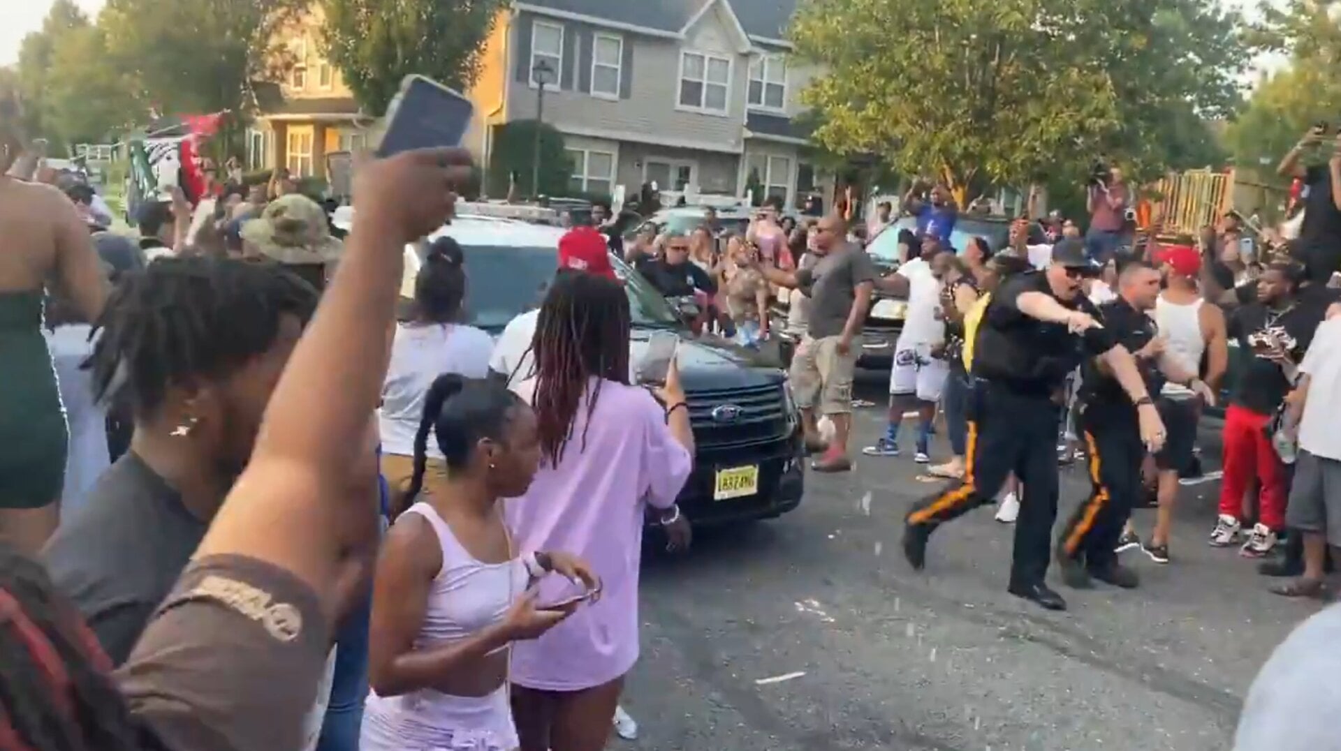 Officers clear a path for a police vehicle containing Edward Cagney  Mathews, under arrest on charges of bias intimidation and trespassing, after protesters surrounded his residence on July 5.