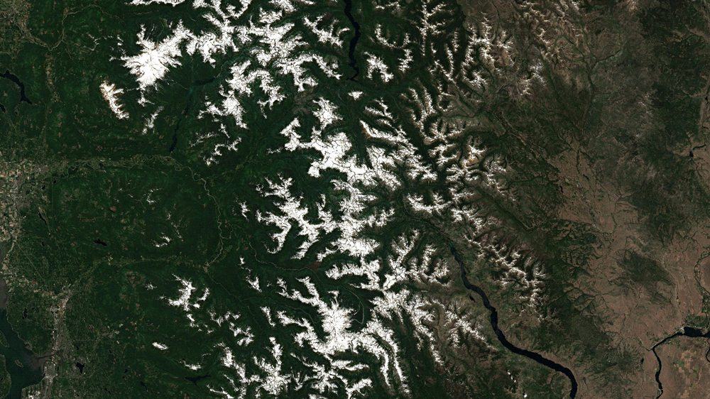 A satellite composite showing the North Cascades on June 26, 2021 and July 11, 2021. A wildfire is also visible.