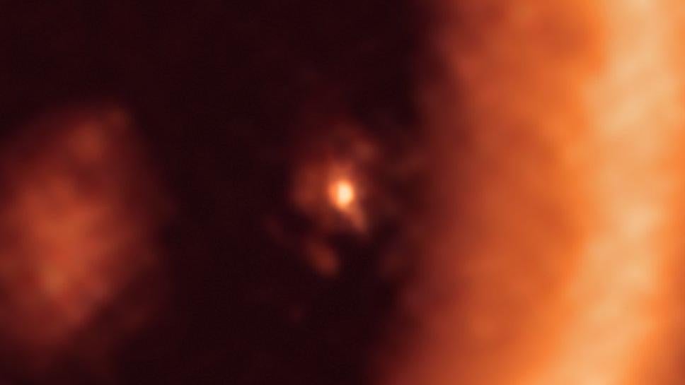 At center, the circumplanetary disk surrounding the giant protoplanet. The larger circumstellar ring dominates the right-hand portion of the ALMA image. 