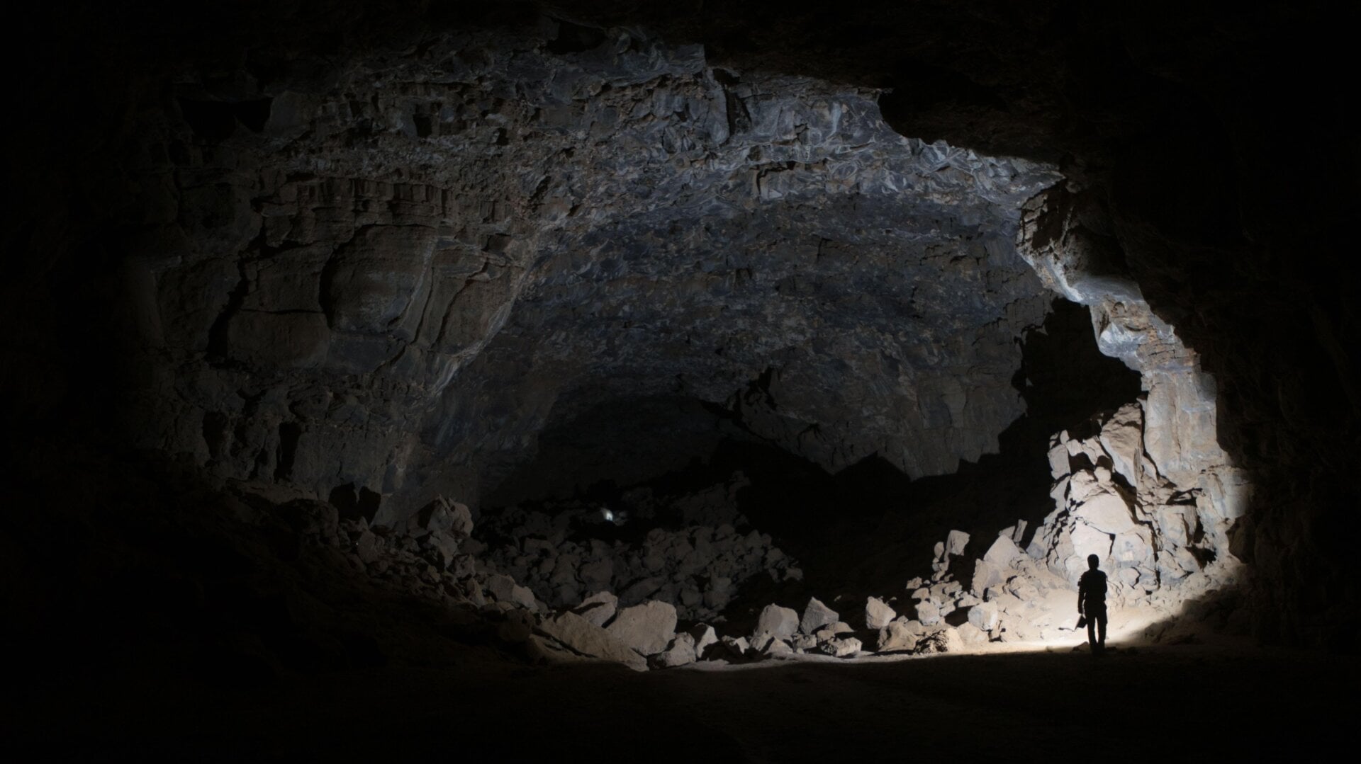 The a cavernous opening in the Umm Jirsan lava tube, illuminated by a researcher’s light.