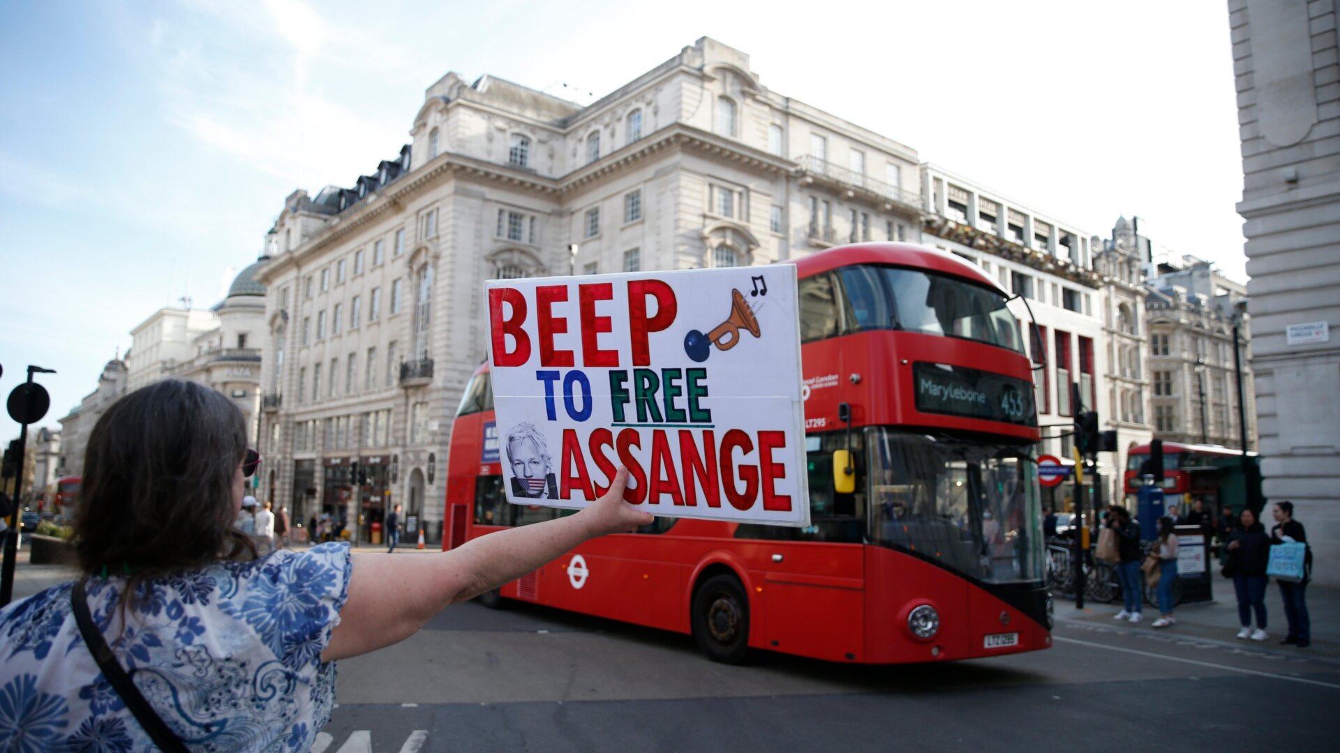 A demonstrator holds a placard that says “Beep to Free Assange” at Piccadilly Circus on April 17, 2021 in London, England.
