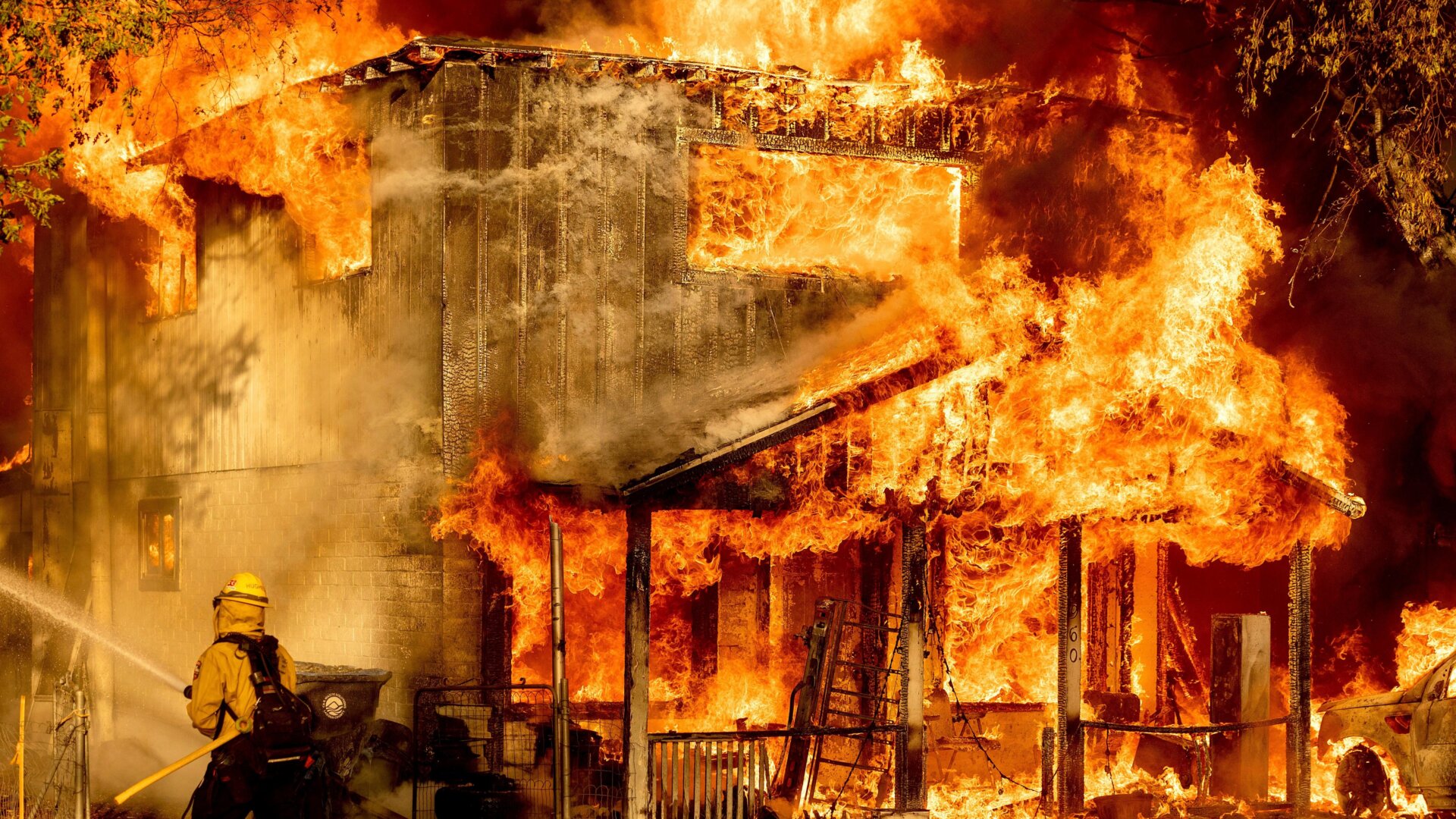 A firefighter sprays water while trying to stop the Sugar Fire, part of the Beckwourth Complex Fire, from spreading.