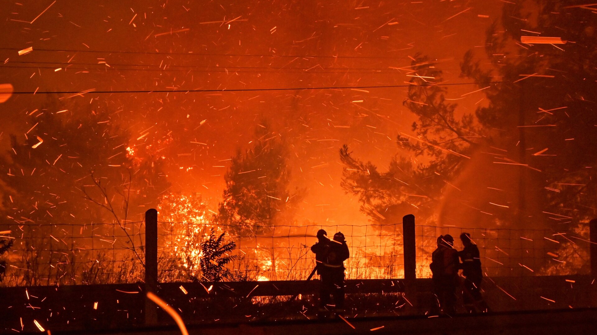 Firefighters try to put out a wildfire as flames spread over a highway on August 5, 2021, in northern Athens, Greece.