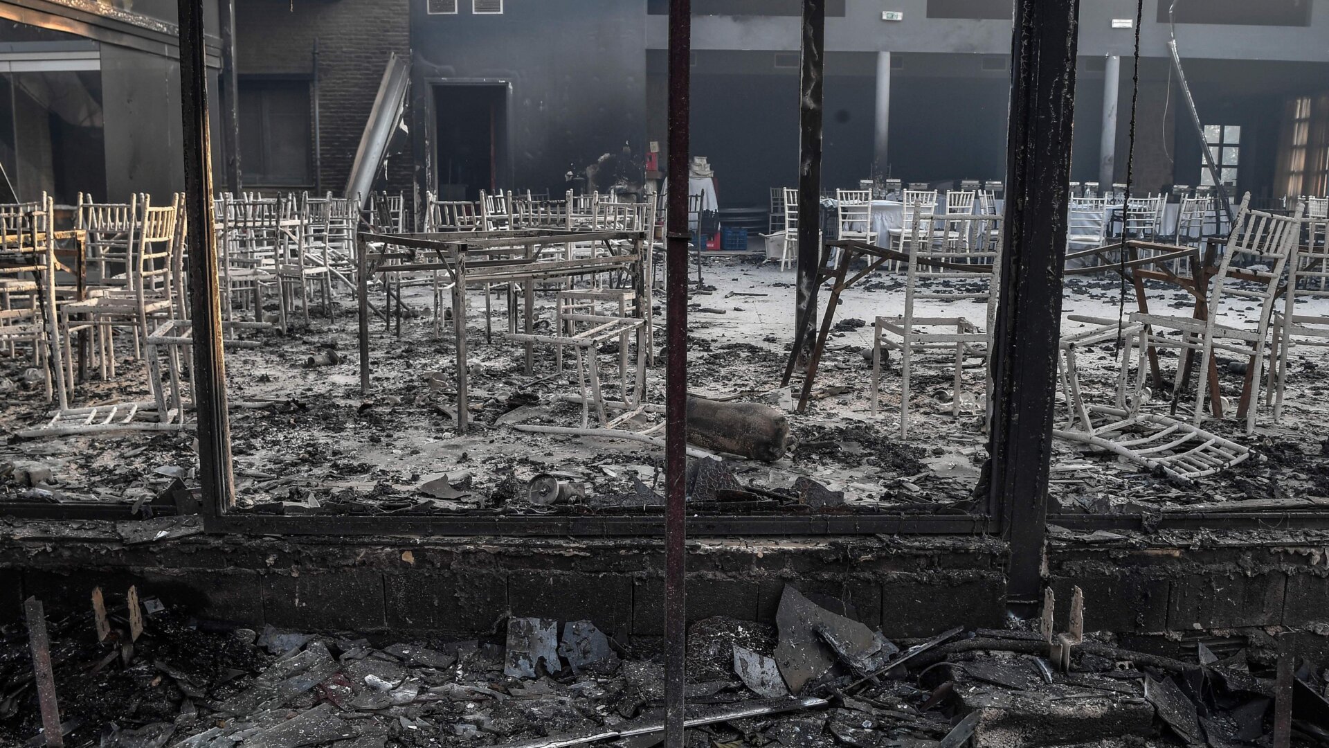 Burned chairs and tables inside a partially burned down tavern in Varybombi.