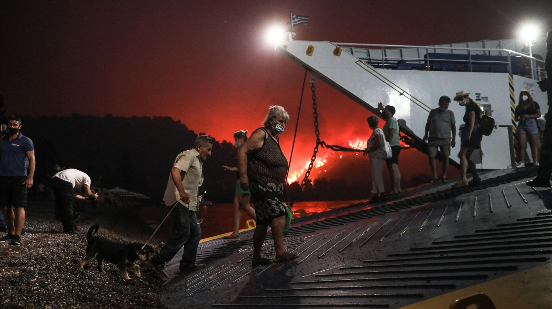 People board a ferry prior to an evacuation as a wildfire approaches the seaside village of Limni on the island of Evia, Greece, on August 6, 2021.