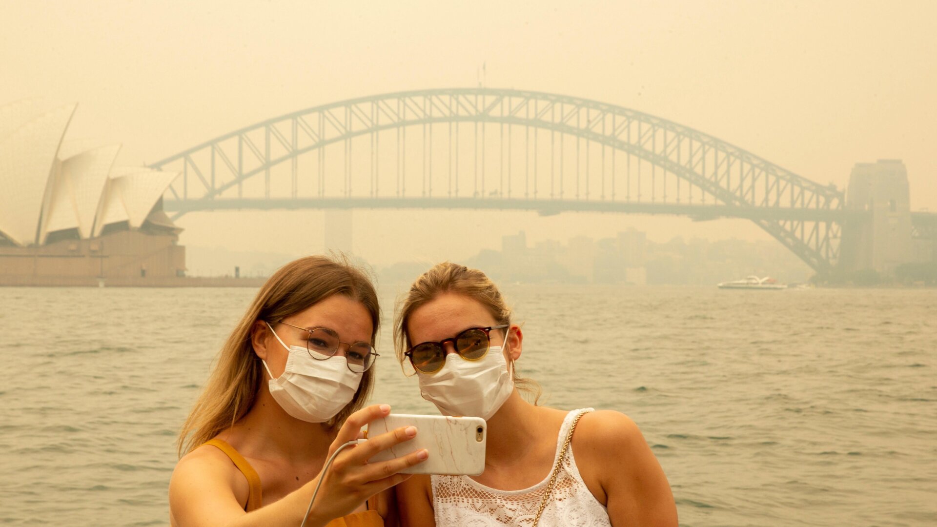 Tourists take a selfie while wearing face masks due to heavy smoke (this is pre-pandemic!) on Dec. 19, 2019 in Sydney, Australia.