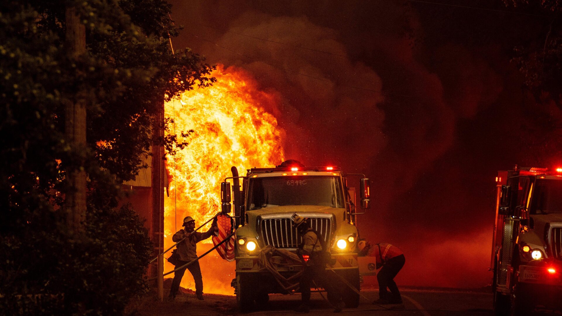 A firefighter saves an American flag as flames consume a home during the Dixie fire in Greenville, California.