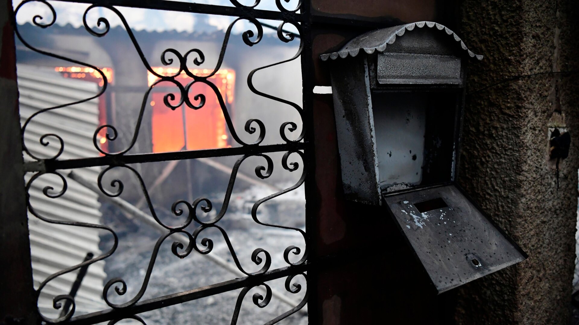 Flames burn inside a house during a wildfire in Adames area.