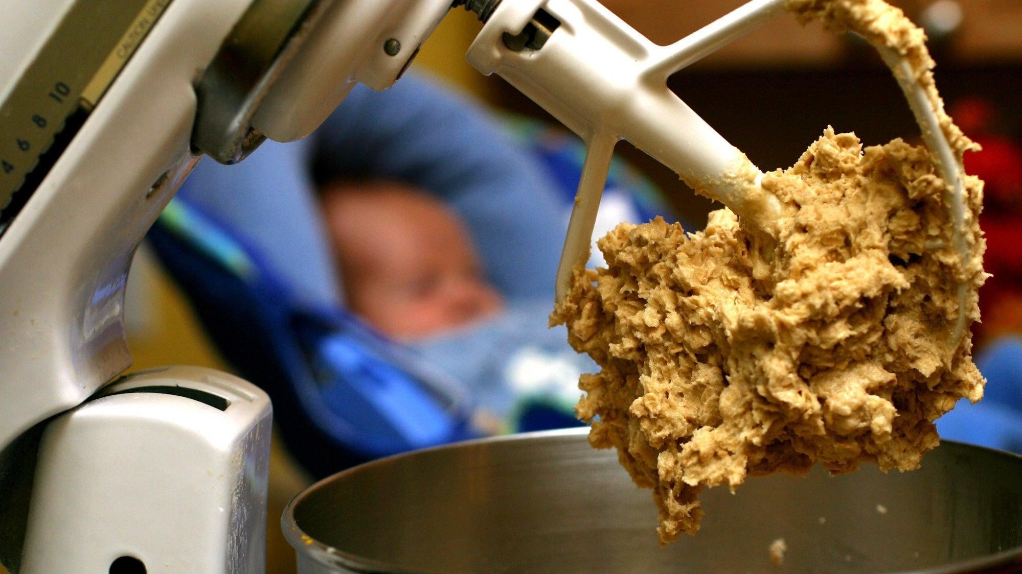 Raw cookie dough clings to the beaters of a standing mixer