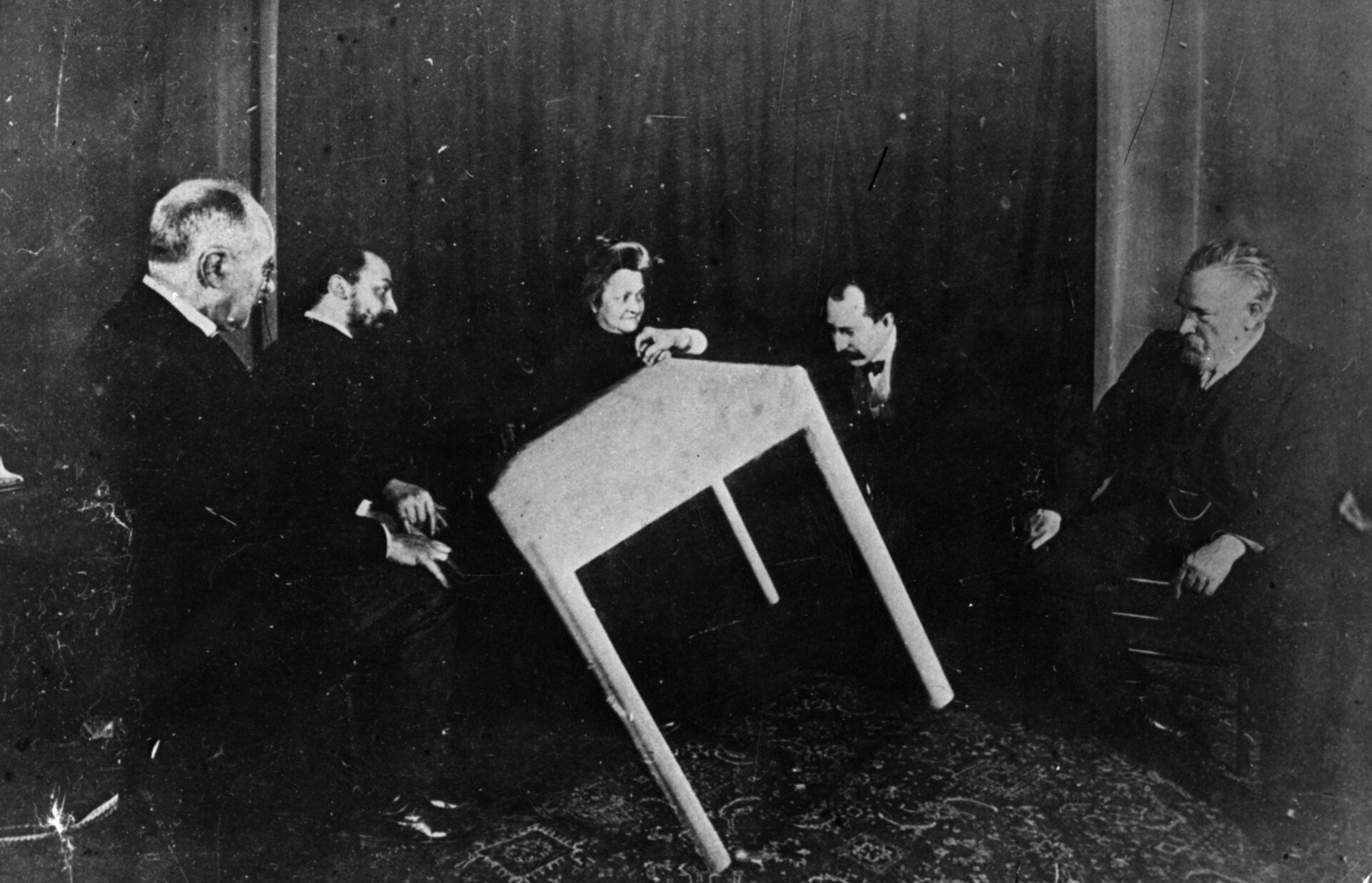 In this vintage photograph (circa 1900), a table apparently moves of its own accord during a séance in Paris.