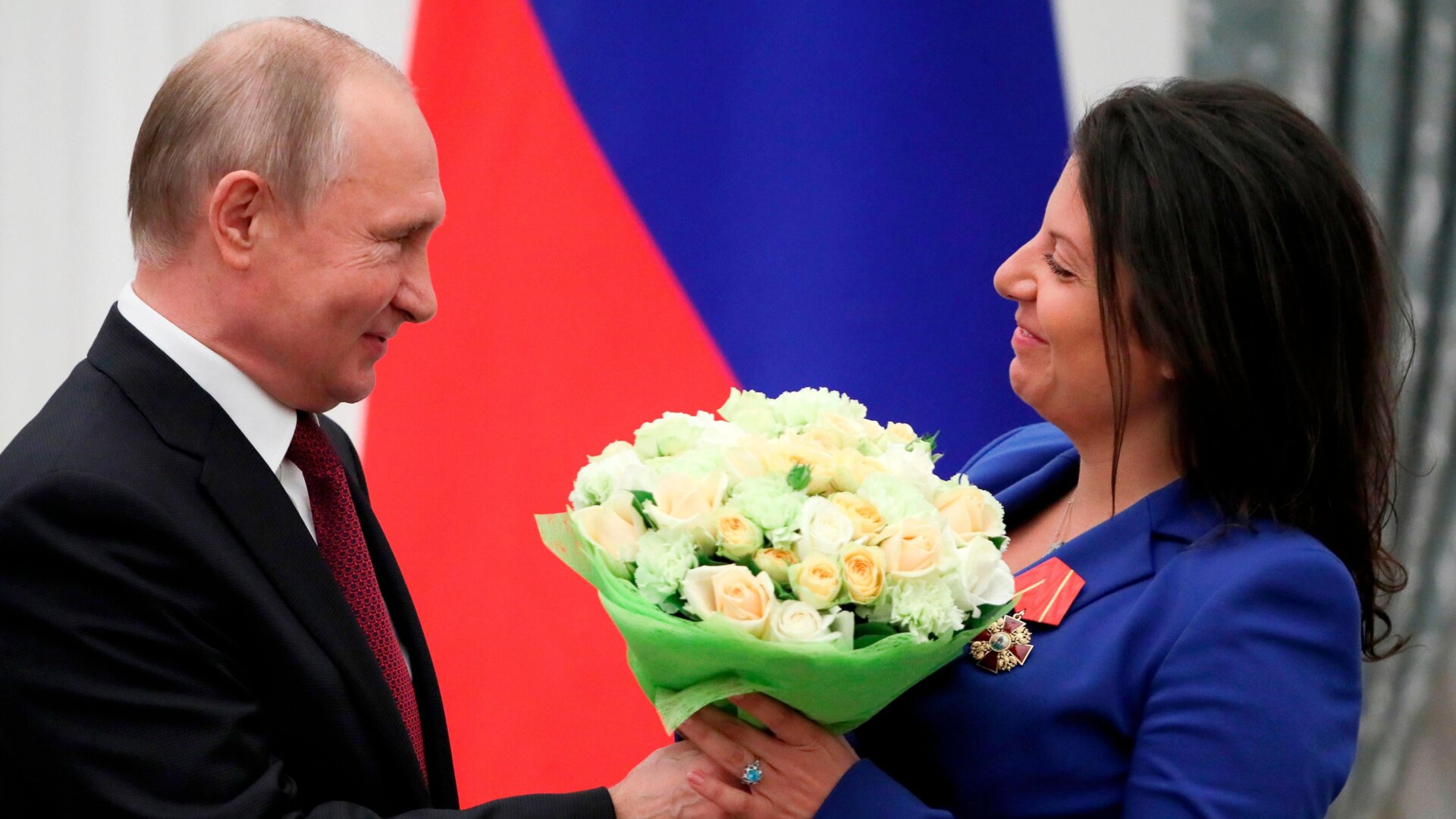 Russian President Vladimir Putin presents flowers to editor-in-chief of Russian state broadcaster RT, Margarita Simonyan, at the Kremlin in Moscow on May 23, 2019.