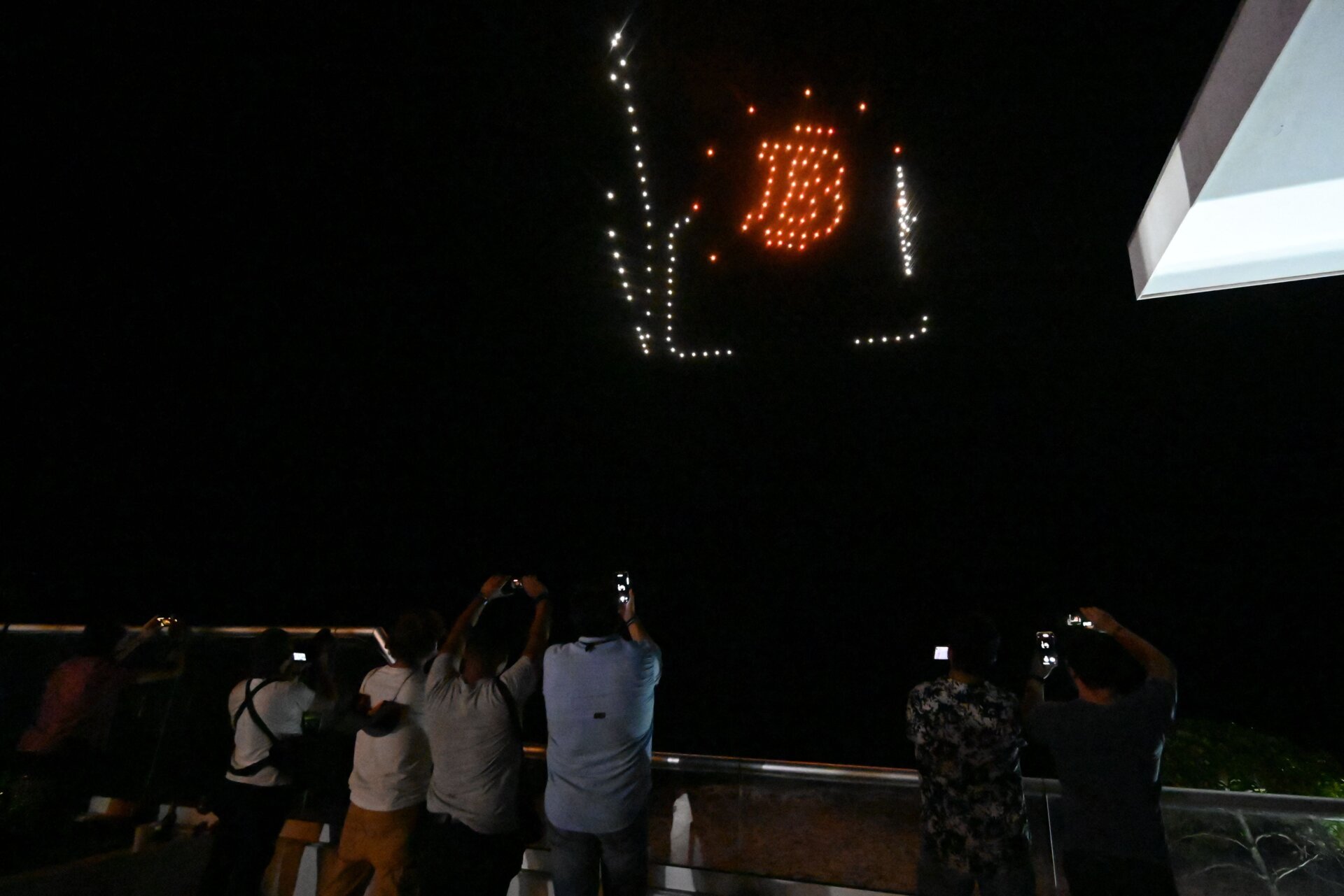 People take pictures as illuminated drones form figures inspired by the bitcoin logo at a reception hosted by American cryptocurrency developer and billionaire Brock Pierce on the first day of bitcoin’s implementation as a currency in El Salvador, in El Sunzal Beach on September 7, 2021. 