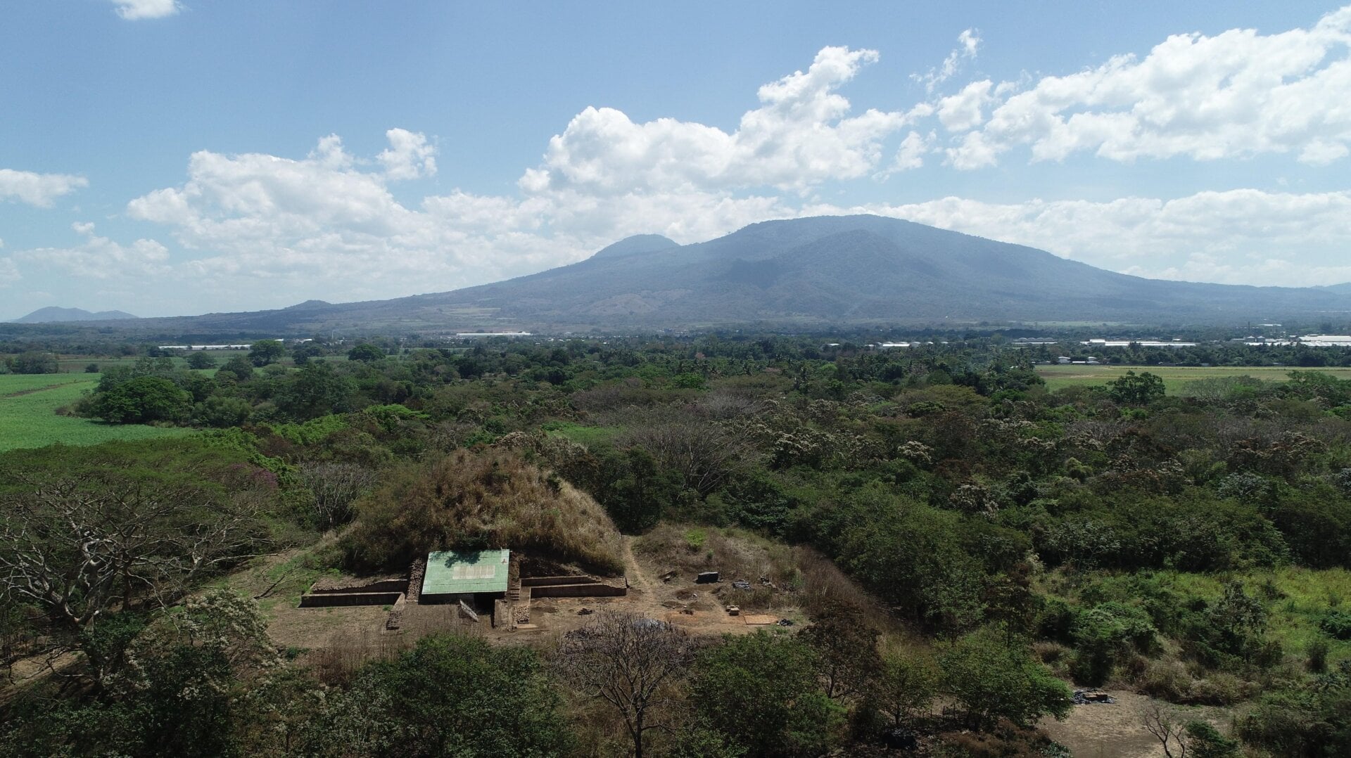 The pyramid, known as the Campana structure, with volcanic mountains in the background.