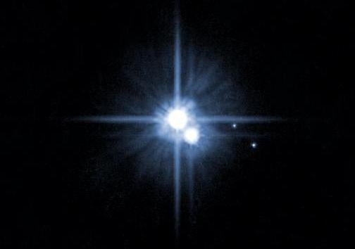 Pluto (center) and three of its moons, as seen by Hubble in 2005.