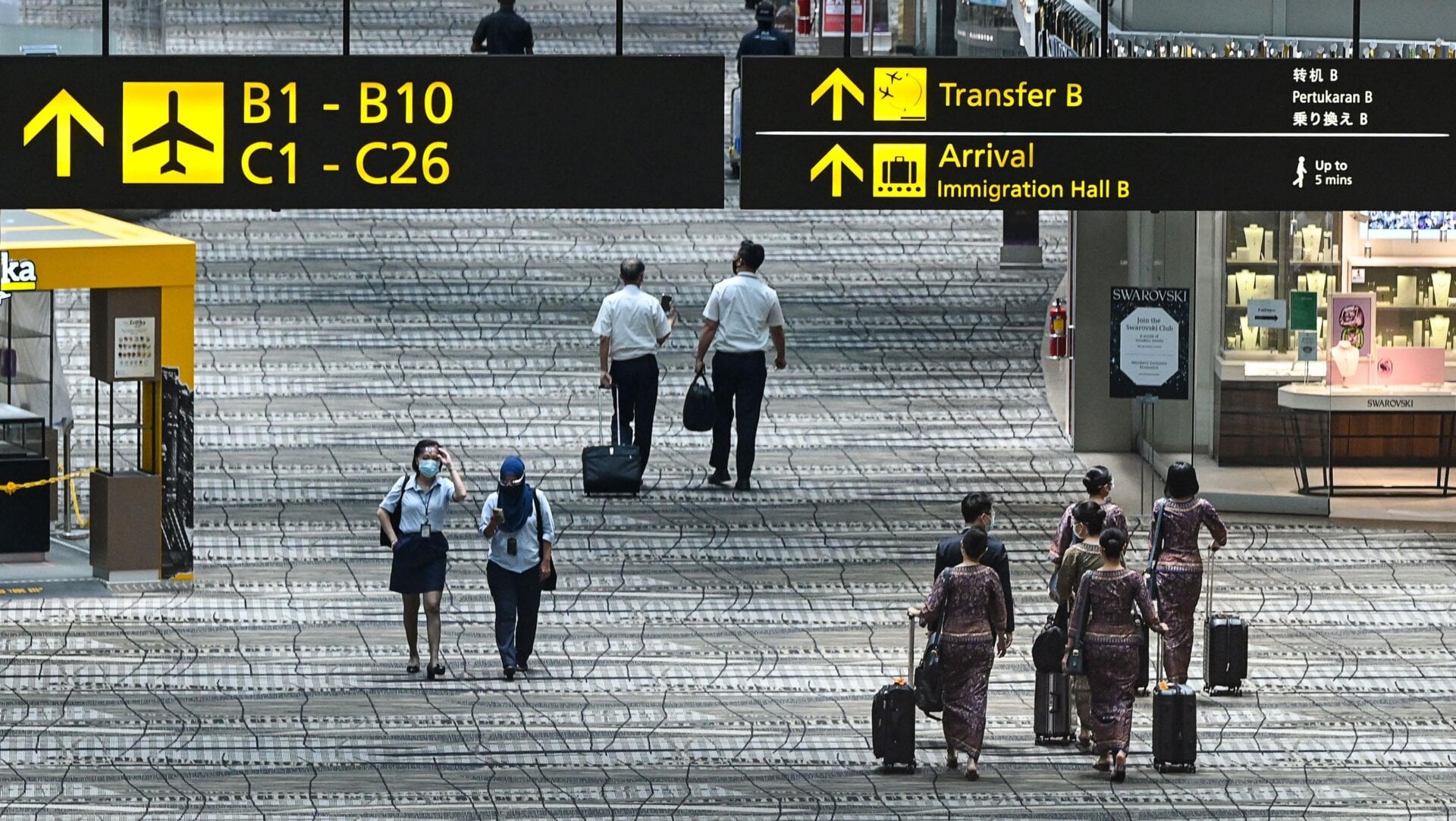 Singapore Airlines flight crew members walk along the transit hall of the Changi International Airport in Singapore on September 3, 2021.