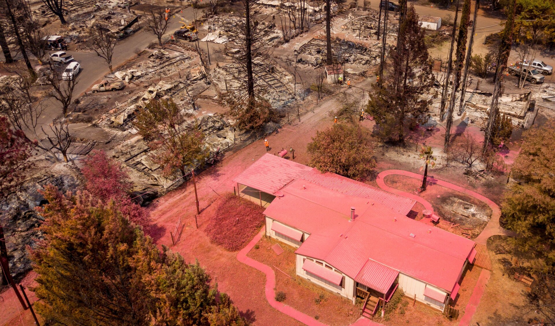 An aerial view shows a home covered in fire retardant near dozens of properties destroyed at the Creekside Mobile Home Park after the Cache fire ripped through the area in Clearlake, California, on Aug. 19, 2021