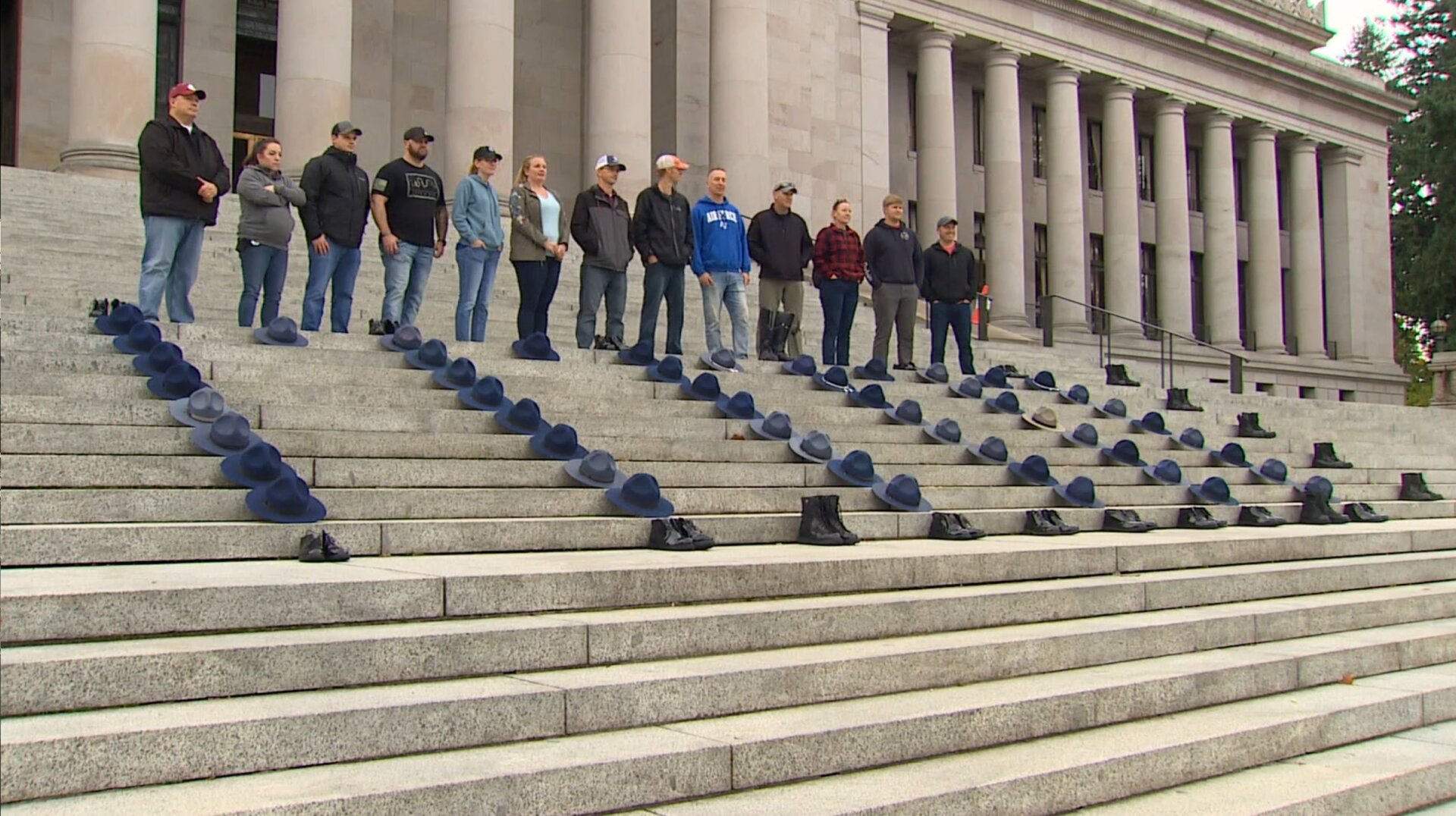 Anti-vax former Washington State Patrol troopers and other employees lay hats of their fired colleagues on the state Capitol in a protest against the state’s employee vaccination requirement.