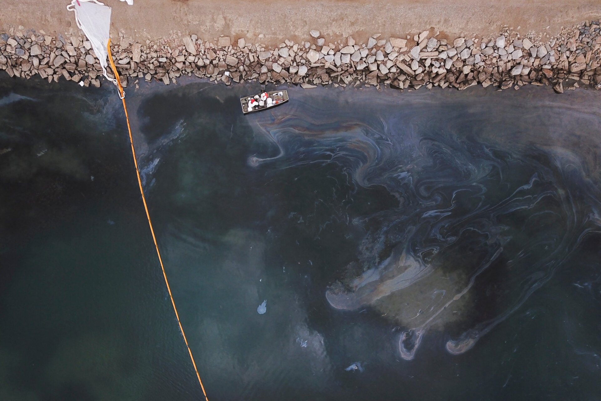 Environmental response crews cleaning up oil that flowed near the Talbert marsh and Santa Ana River mouth, creating a sheen on the water.