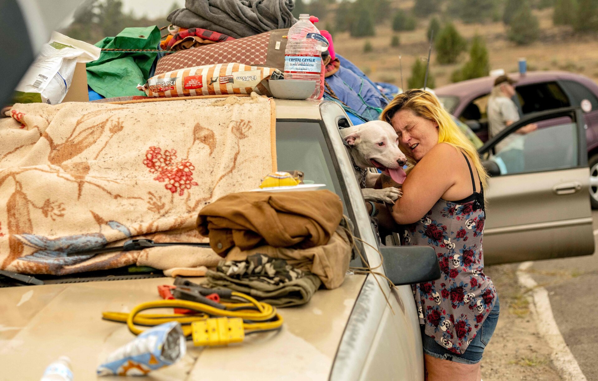 Evacuated Chester resident April Phillips hugs their family dog at an evacuation center for the Dixie fire in Susanville, California, on Aug. 6, 2021.