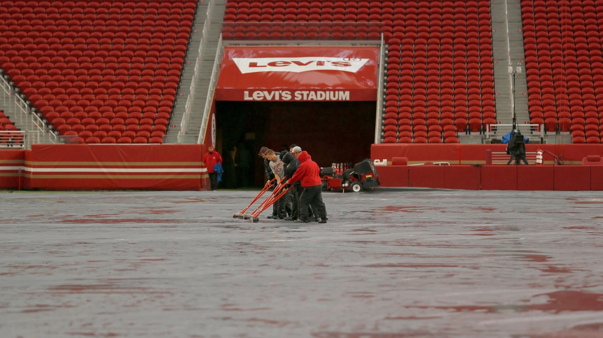 Workers push water off a tarp covering the field from rain at Levi’s Stadium before an NFL football game between the San Francisco 49ers and the Indianapolis Colts in Santa Clara, California.