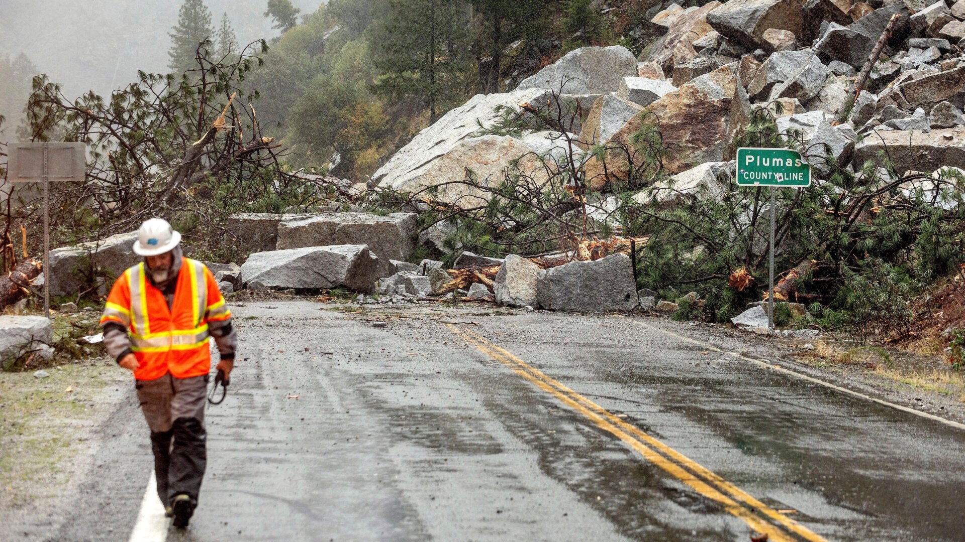 Caltrans maintenance supervisor Matt Martin walks by a landslide covering Highway 70 in the Dixie Fire zone.