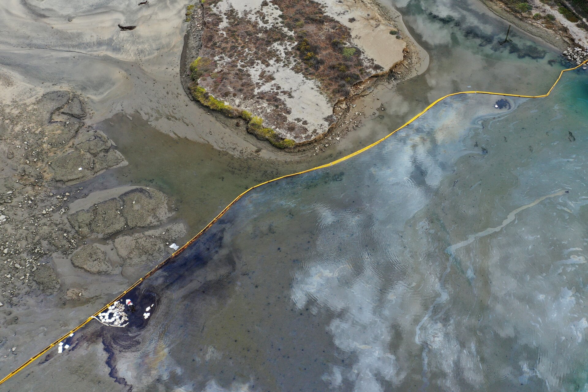 In an aerial view, a containment boom blocks oil-contaminated water in the area of the Talbert Marsh wetlands.